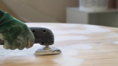Eski bir masanın yüzeyini öğütme makinesiyle öğütmek. Mobilya onarımı, DIY onarımı, kendi kendine tamir edilmesi ve ev dekorasyonu.