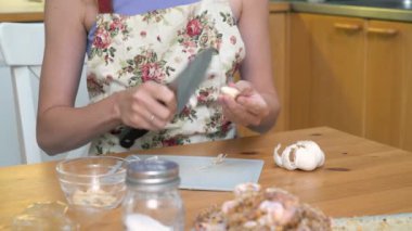 Bir kadın sarımsağı yakın çekimde bıçakla kesiyor. Salata için sarımsak kesmek ya da et için aromatik baharat olarak.