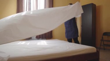 Hizmetçi yatağı kar beyazı bir çarşafla örtüyor. Otel odasında yatak değiştiren bir kadın hizmetçi. Çalışan bir pansiyonda oda temizliyor. Otel sektöründe kaliteli hizmet kavramı