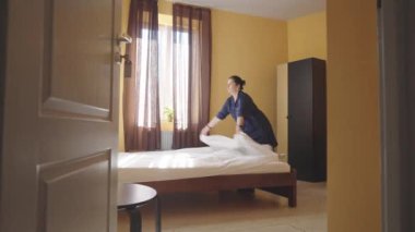 Hizmetçi yatağı kar beyazı bir çarşafla örtüyor. Otel odasında yatak değiştiren bir kadın hizmetçi. Çalışan bir pansiyonda oda temizliyor. Otel sektöründe kaliteli hizmet kavramı