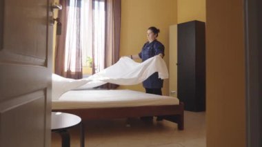 Hizmetçi yatağı kar beyazı bir çarşafla örtüyor. Otel odasında yatak değiştiren bir kadın hizmetçi. Çalışan bir pansiyonda oda temizliyor. Otel sektöründe kaliteli hizmet kavramı