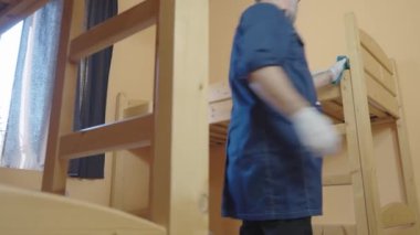 Orta yaşlı bir erkek otel odasını temizliyor. Otel işi konsepti üzerine ticari temizlik şirketi.