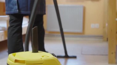 Orta yaşlı bir erkek otel odasını elektrikli süpürgeyle temizliyor. Otel işi konsepti üzerine ticari temizlik şirketi.