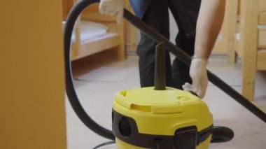 Orta yaşlı bir erkek otel odasını elektrikli süpürgeyle temizliyor. Otel işi konsepti üzerine ticari temizlik şirketi.