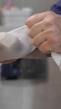 Orta yaşlı, lastik koruyucu eldivenli bir erkek hizmetçi otel odasında duşu temizliyor. Otel işi konsepti üzerine ticari temizlik şirketi.