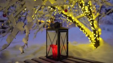 Evin karla kaplı sıcacık avlusu Noel ışıkları ve mumlarla süslenmiş..