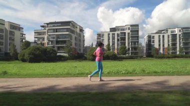 Finlandiya 'da bir şehir parkında spor kıyafetleri içinde koşan atletik olgun bir kadın. Dışarıda koşan spor kıyafetleriyle koşan yaşlı bir bayan koşucu. Sağlıklı yaşam tarzı kavramı