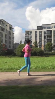 Finlandiya 'da bir şehir parkında spor kıyafetleri içinde koşan atletik olgun bir kadın. Dışarıda koşan spor kıyafetleriyle koşan yaşlı bir bayan koşucu. Sağlıklı yaşam tarzı kavramı