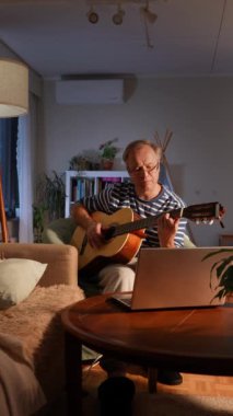 Orta yaşlı bir adam rahat bir odada oturuyor ve akustik gitar çalmayı öğrenmeye odaklanıyor. Önündeki küçük bir masaya yerleştirilmiş dizüstü bilgisayarında bir video dersi izliyor.