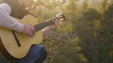 Orta yaşlı bir adam gün batımında Finlandiya ormanında bir uçurumun tepesinde gitar çalar. Sahne, ağaçların arasından süzülen batan güneşin yumuşak parıltısıyla huzurlu bir çevre yakalıyor..