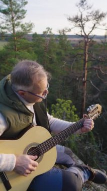 Orta yaşlı bir adam gün batımında Finlandiya ormanında bir uçurumun tepesinde gitar çalar. Sahne, ağaçların arasından süzülen batan güneşin yumuşak parıltısıyla huzurlu bir çevre yakalıyor..
