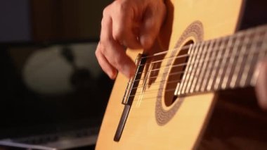 Akustik gitarın tellerindeki bir gitaristin elleri. Sıcak bir ışık, rahat bir atmosfer..