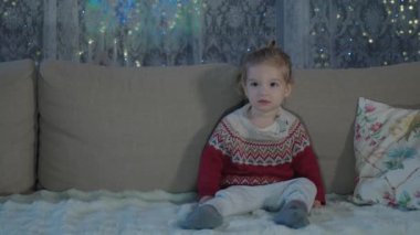 Küçük bir çocuk sıcak bir oturma odasında akşamları tek başına oturur ve televizyon izler. Oda, televizyonun parıltısıyla hafifçe aydınlatılıyor. Çocukların odaklanmış ifadesini vurguluyor..