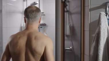 Duştan sonra modern bir banyoda kendini havluyla kurutan orta yaşlı bir adam. Günlük rutin, hijyen ve rahatlama. Yaşam tarzı, kişisel bakım ve kişisel bakım..