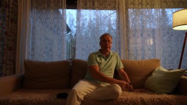 Gece boyunca oturma odasındaki rahat bir kanepede oturan orta yaşlı bir adam. Elinde bir televizyon kumandası var. Uzun bir günün ardından rahatlama anının tadını çıkarıyor. Boş zaman