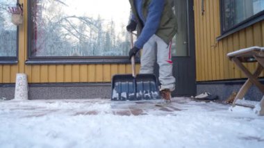 Orta yaşlı bir adam Finlandiya 'da kışları evinin arka bahçesinde kar temizliyor.