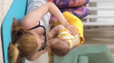 Genç, zinde bir anne, bebeği ile birlikte bebek odasında spor yapıyor. Doğum sonrasındaki genç bir anne için bir takım egzersizler. Spor, annelik, doğum sonrası ve aktif yaşam tarzı..