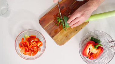 Parlak, rahat bir mutfakta yemek hazırlayan bir adam. O, yakındaki bir sepetin içinde taze ürünlerle ahşap bir tahtada sebze kesiyor. Oda bitkiler ve çiçeklerle süslenmiş, sıcak ve...