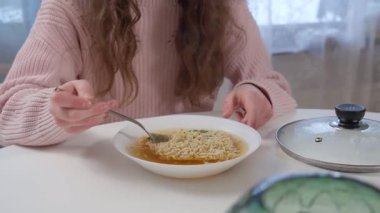 Uzun kahverengi saçlı genç bir kız hazır erişte yiyor. Sağlıksız fast food seçenekleri, yapay katkı maddeleri ve çocuklar için sağlıklı beslenmenin önemi..