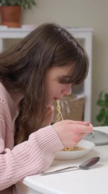 Uzun kahverengi saçlı genç bir kız hazır erişte yiyor. Sağlıksız fast food seçenekleri, yapay katkı maddeleri ve çocuklar için sağlıklı beslenmenin önemi..