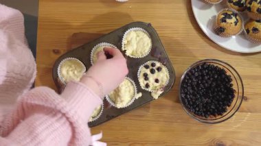 Bir kız sıcak bir mutfakta yabanmersinli kek pişiriyor..