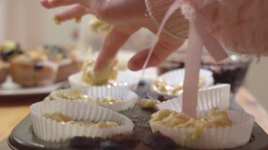 Kapkek poşetlerini sıcak bir mutfakta kek hamuruyla dolduran bir kızın yakın çekimi..