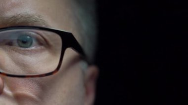 Göz yorgunluğunu azaltmak için bilgisayar gözlüğü takan, internete göz gezdiren, haberleri okuyan, geç saatlere kadar ekranda çalışan odaklanmış orta yaşlı adama yakın çekim. Dolli 'yi izliyorum.