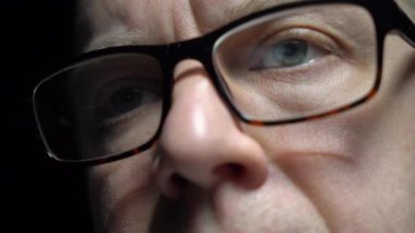 Göz yorgunluğunu azaltmak için bilgisayar gözlüğü takan, internete göz gezdiren, haberleri okuyan, geç saatlere kadar ekranda çalışan odaklanmış orta yaşlı adama yakın çekim. Dolli 'yi izliyorum.