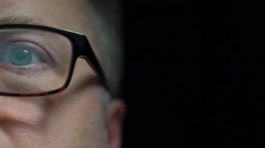 Göz yorgunluğunu azaltmak için bilgisayar gözlüğü takan, internete göz gezdiren, haberleri okuyan, geç saatlere kadar ekranda çalışan odaklanmış orta yaşlı adama yakın çekim. Dolli 'yi izliyorum.