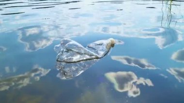 Doğadaki plastik çöpler. Suda yüzen kullanılmış bir şişe. Plastik atık kirliliği orman gölü. Dünya plastik kirliliği krizi konsepti.