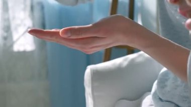 Anne, çocuğun ellerine ve ayaklarına doğal ışık altında nemlendirici krem sürüyor. Nazik cilt bakımı, ebeveyn-çocuk bağı ve sağlıklı cilt koruması. Yakın çekim, sıcak atmosfer, kişisel bakım.