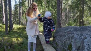 Anne ve çocuk, Fin ormanında birlikte doğa keşfi yaparak yürüyüş yaparlar. Aile gezintisi, doğayla bağlantı. Çevre bilinci ve çevre sevgisi.