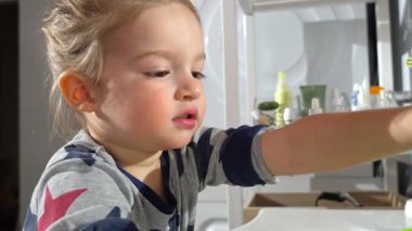 Pijamalı küçük bir çocuk banyo lavabosundan suyla doldurduktan sonra parlak yeşil bir bardaktan su içiyor. Doğal olarak yıldırım ve su damlacıklarının şeffaflığı doğal ve sıcak bir hava katar.