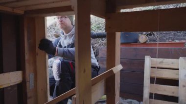 Eski ahır tadilatı sırasında dışarıda ahşap duvar onarımı yapan adam. Yapıyı geliştirmek için el aletleri ve kereste kullanıyor. DIY, İnşaat ve Ev Bakımı.