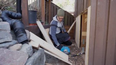 Eski ahır tadilatı sırasında dışarıda ahşap duvar onarımı yapan adam. Yapıyı geliştirmek için el aletleri ve kereste kullanıyor. DIY, İnşaat ve Ev Bakımı.