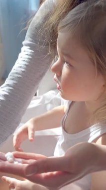 Anne, yumuşak doğal ışıkla çocuğun yüzüne nemlendirici krem sürüyor. Nazik cilt bakımı, ebeveyn-çocuk bağı ve sağlıklı cilt koruması. Yakın çekim, sıcak atmosfer, kişisel bakım ve sağlık.