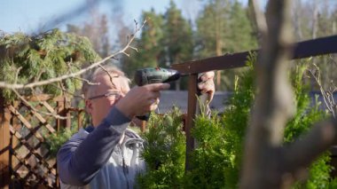 Baharda arka bahçedeki çitlerden koruyucu ağları söken adam.