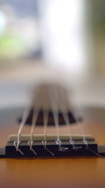 Kalın bir alan derinliği olan klasik gitar tellerine yakın çekim. Dolly, ipleri takip ederken, köprüyü ve dokuyu vurguluyor. Bir müzik aletinin sanatsal ve soyut perspektifi.