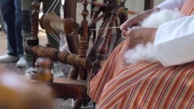 Geleneksel Fin kostümlü bir kadın eski bir iplik makinesi kullanarak iplik çevirir.