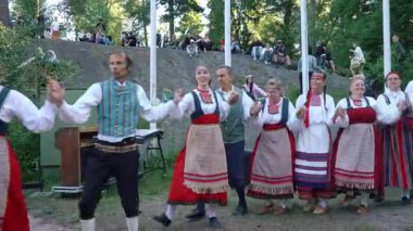 Helsinki, Finlandiya - 21 Haziran 2024: Seurasaari açık hava müzesinde geleneksel yaz ortasında dans eden Fin halk dansçıları. Müzik ve doğal ortam sesi olan video