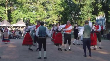 Helsinki, Finlandiya - 21 Haziran 2024: Seurasaari açık hava müzesinde geleneksel yaz ortasında dans eden Fin halk dansçıları. Müzik ve doğal ortam sesi olan video
