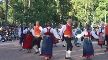 Helsinki, Finlandiya - 21 Haziran 2024: Seurasaari açık hava müzesinde geleneksel yaz ortasında dans eden Fin halk dansçıları. Müzik ve doğal ortam sesi olan video