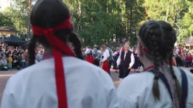Helsinki, Finlandiya - 21 Haziran 2024: Seurasaari açık hava müzesinde geleneksel yaz ortasında dans eden Fin halk dansçıları. Müzik ve doğal ortam sesi olan video