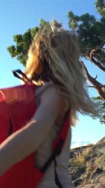 Açık havada kayalık bir yolda gülümseyen genç bir kadın, yaz macerasının tadını çıkarıyor, ortağını güneşli bir yaz yürüyüşünde vahşi kayalıklarda onu takip etmeye davet ediyor. Kaygısız yaz macera anı.