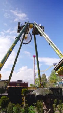 Helsinki, Finlandiya 29 Mayıs 2025: Swingi sarkacı Linnanmaki lunaparkında hareket halindedir. Arka planda hız trenleri ve yaz ziyaretçilerinin olduğu açık bir gökyüzü altında yüksek hız heyecanı.