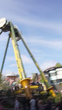 Helsinki, Finlandiya 29 Mayıs 2025: Swingi sarkacı Linnanmaki lunaparkında hareket halindedir. Arka planda hız trenleri ve yaz ziyaretçilerinin olduğu açık bir gökyüzü altında yüksek hız heyecanı.