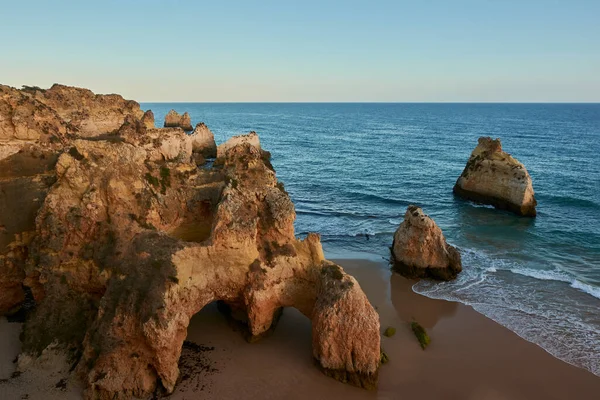 Amazing view of the limestone rocks on secluded beach, Praia dos Tres Irmaos, at sunset. Alvor village, Portugal