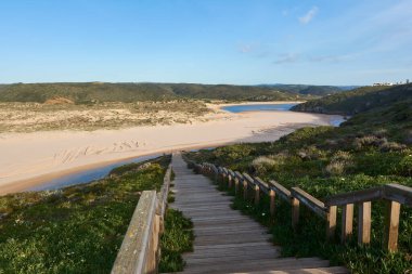 Önünde tahta bir merdiven olan Ribeira de Aljezur nehrinin güzel manzarası. Praia da Amoreira, Portekiz