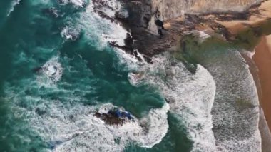 Kayalara çarpan okyanus dalgalarının yukarıdan aşağı görüntüsü. Yavaş çekim görüntüleri