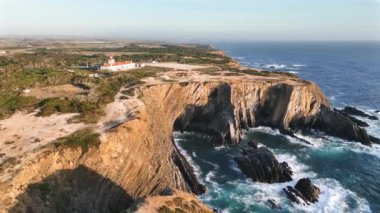 Deniz feneri Cabo Sardao 'nun altın ışıktaki muhteşem manzarası. Deniz mavisi okyanus suyu, büyük kayalar ve kayalıklar. Alentejo, Portekiz